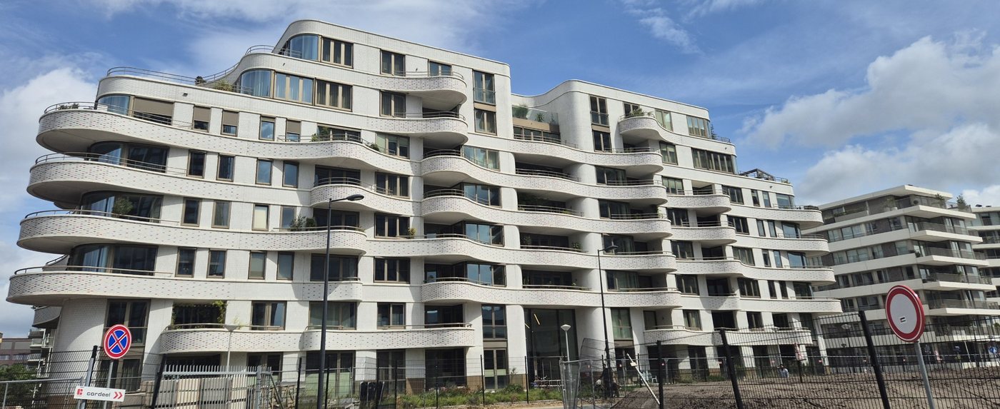 Wave-shaped white apartment block with curved balconies and uPVC windows