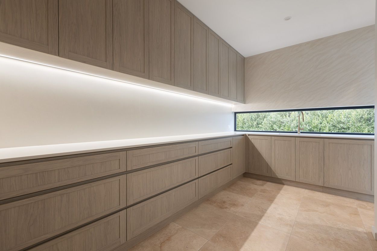 Butler's pantry with oak cabinetry and a long, low black-framed window above the bench