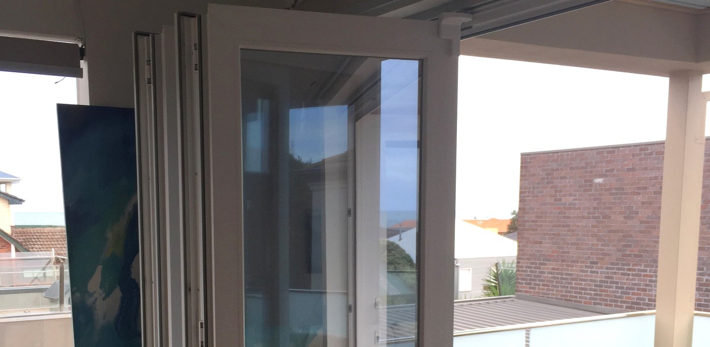 White uPVC bifold doors folded back against the wall, opening the living room to a covered balcony