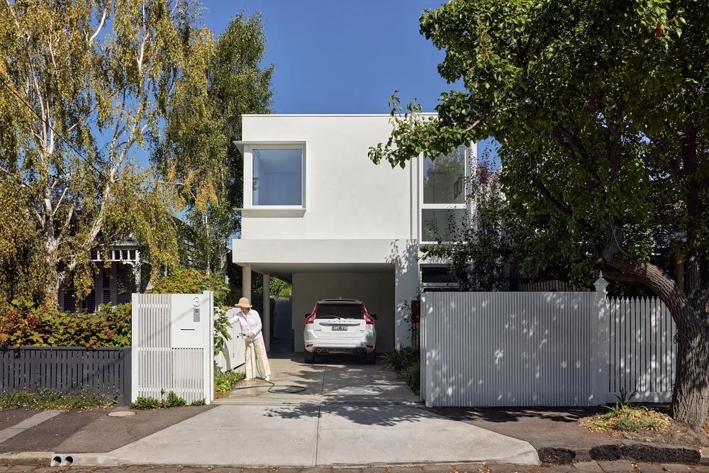 White rendered two-storey home with a projecting white-framed window above the carport