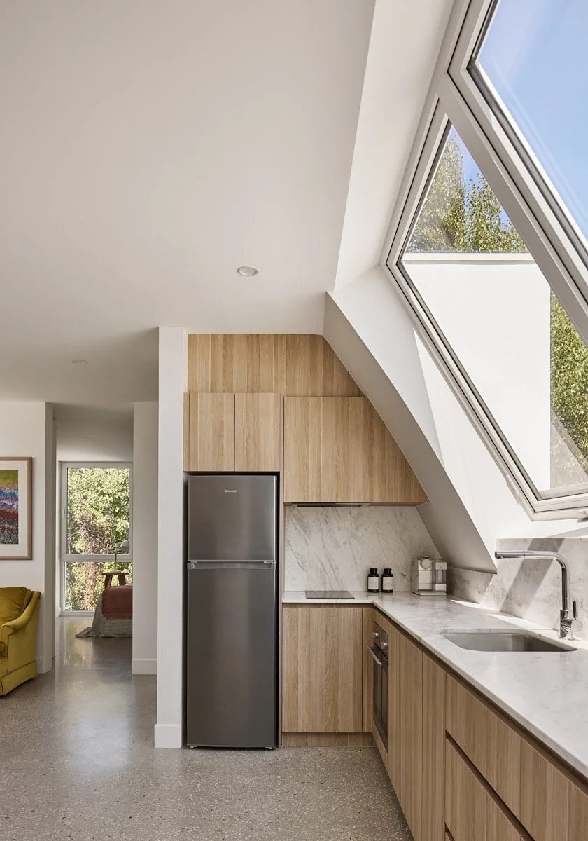 Kitchenette under a sloping ceiling with angled white uPVC windows