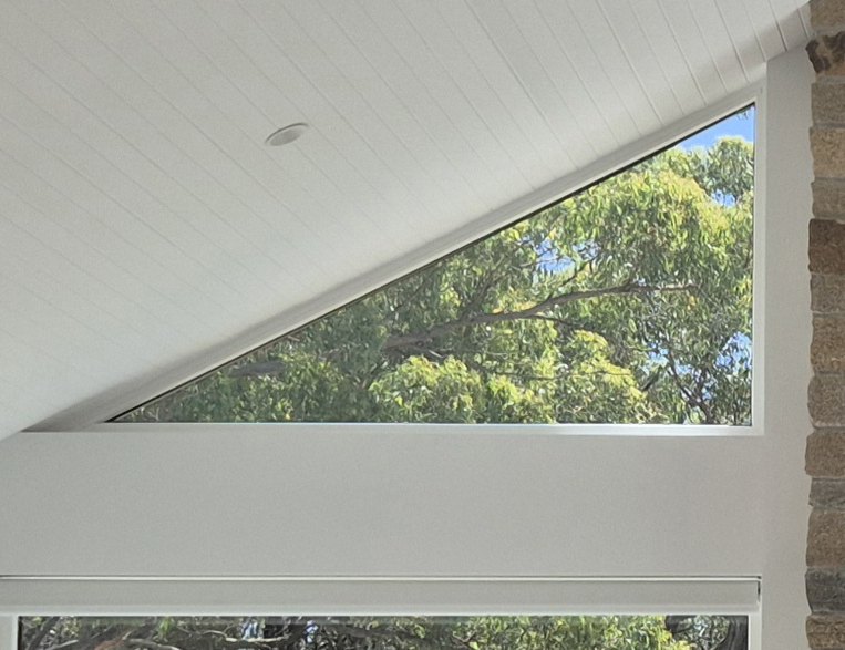 White uPVC raked window following a cathedral ceiling, with a fixed window below