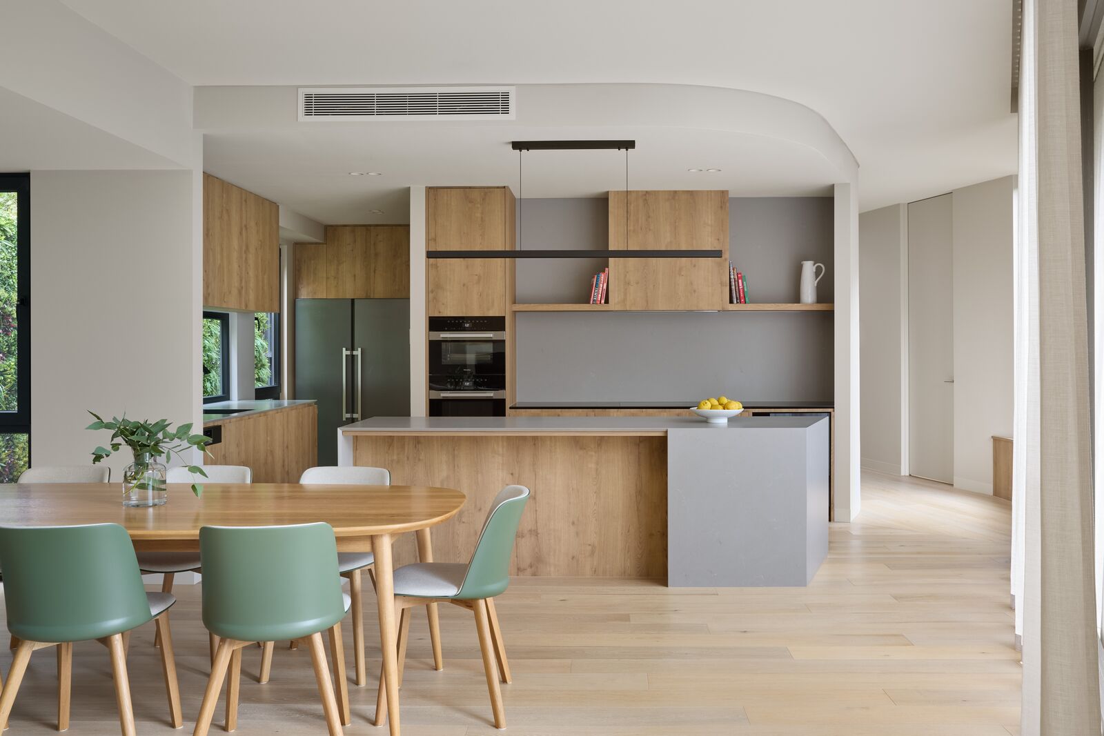 Open-plan kitchen and dining room with timber joinery under a curved ceiling