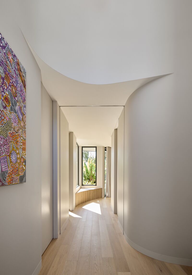 Curved hallway leading to a window seat beside a tall black-framed window