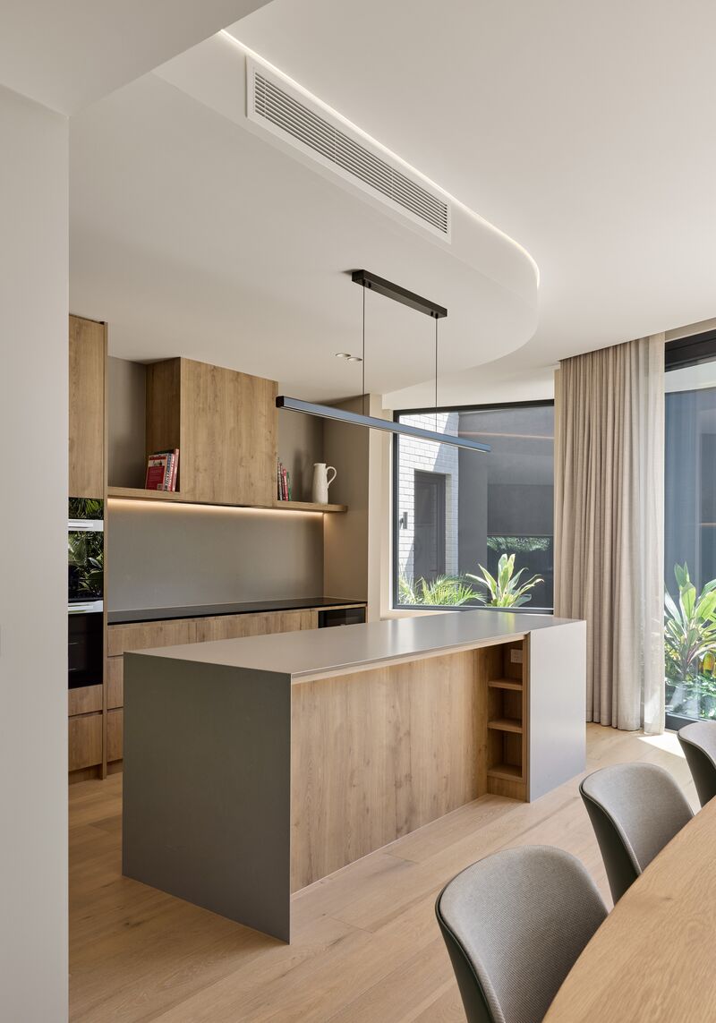 Kitchen island beside a large corner window and floor-to-ceiling glazing onto the courtyard