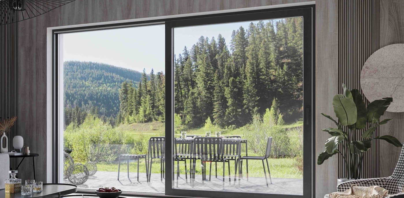 Large black-framed Smart Slide door in a timber-panelled living room, looking out to a terrace and pine forest